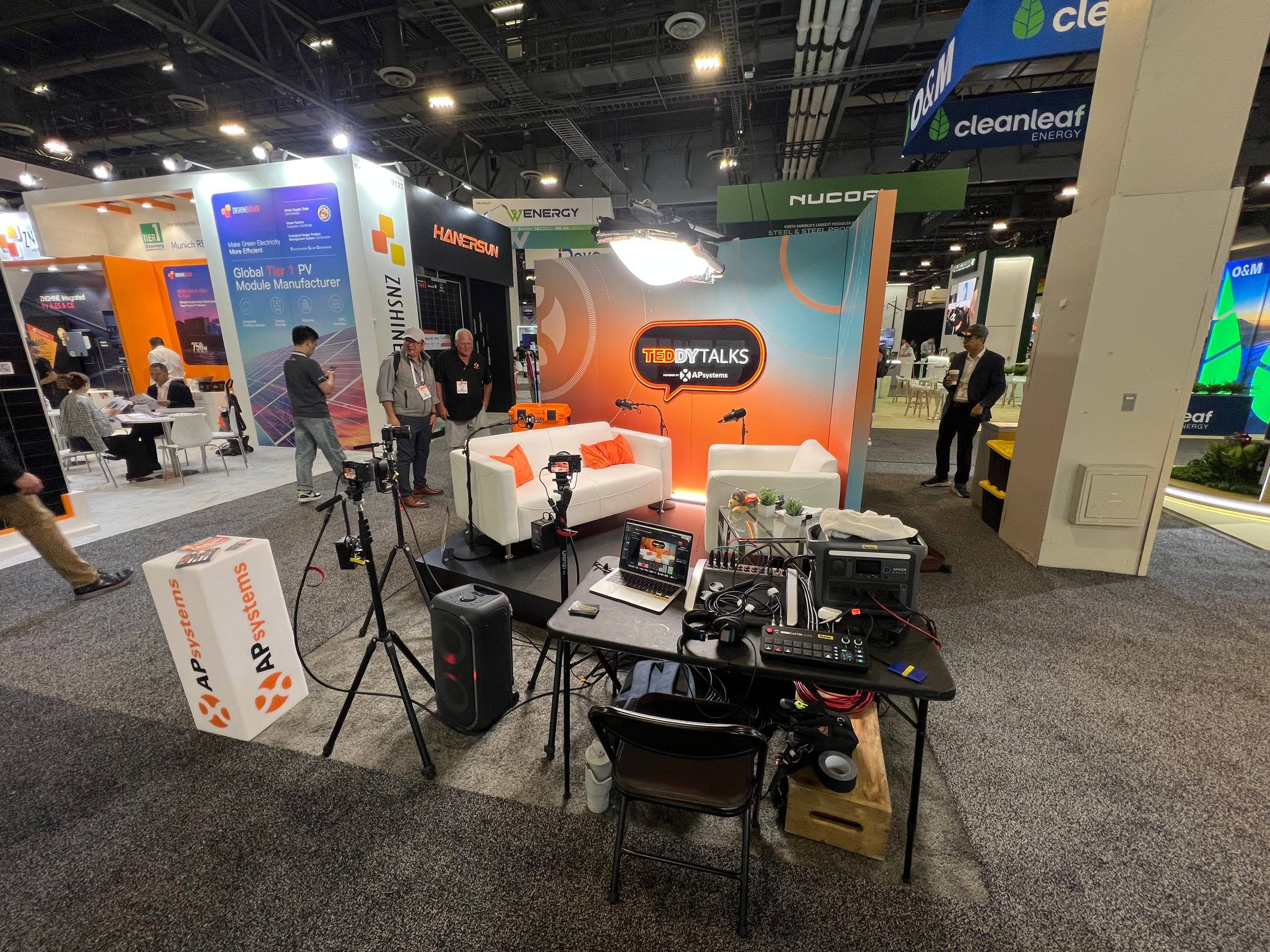 Wide view of the AP Systems podcast booth with cameras, lights and the engineering desk at RE+