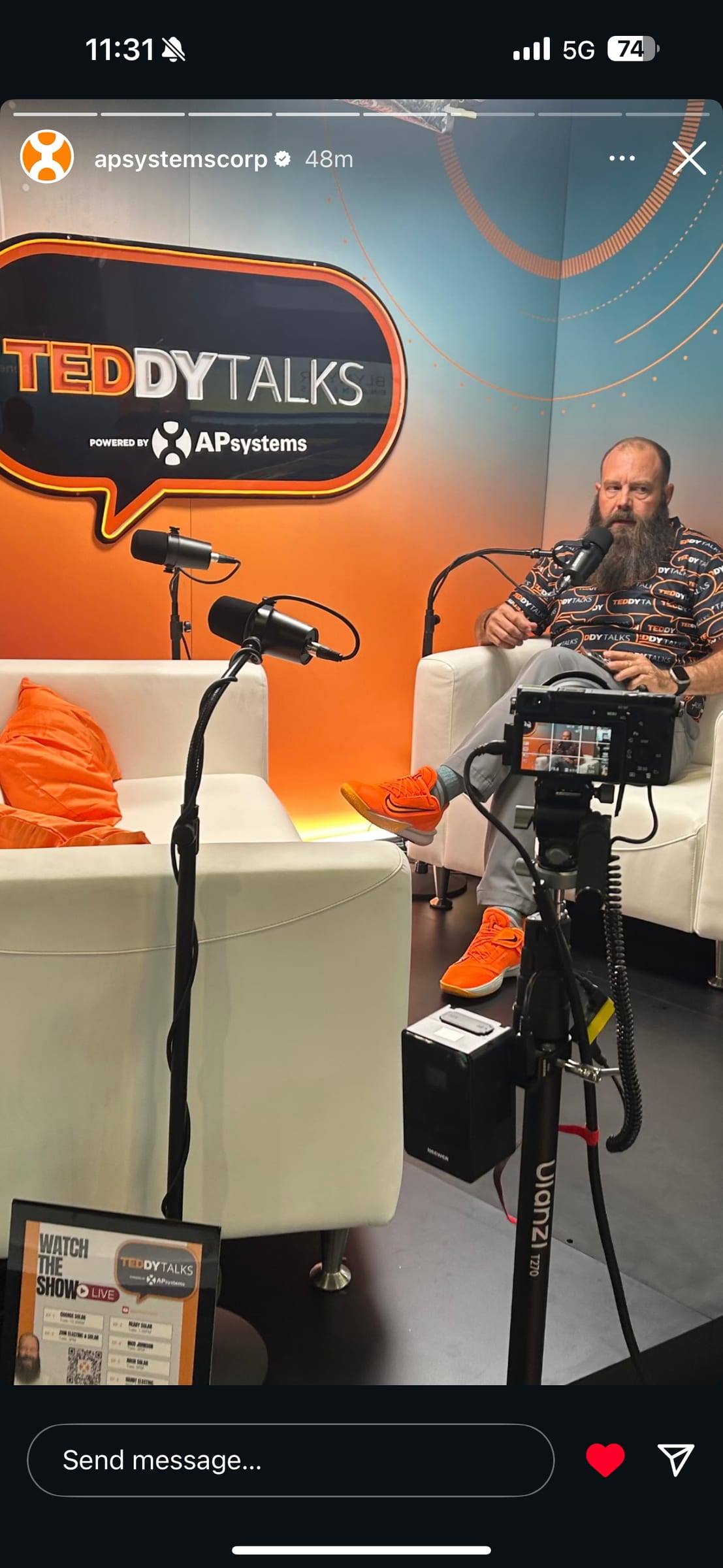 A dynamic podcast mic on a stand in front of a guest, with the camera monitor in the foreground