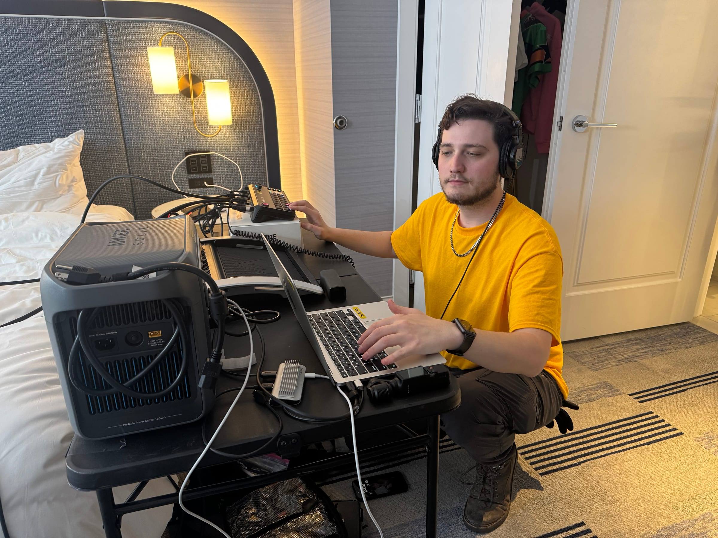 Travis Flesher running audio and video from a compact desk in a hotel room, powered by a portable battery station