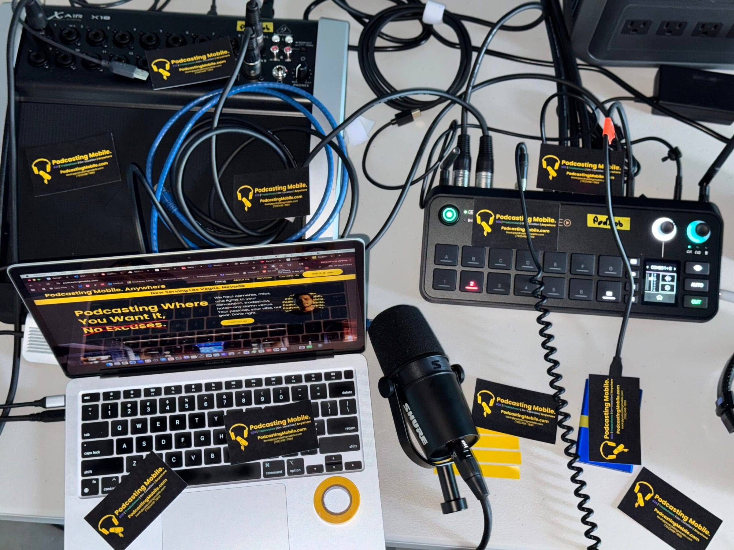The Podcasting Mobile kit laid out: video switcher, Shure podcast mic, laptop, cables and business cards