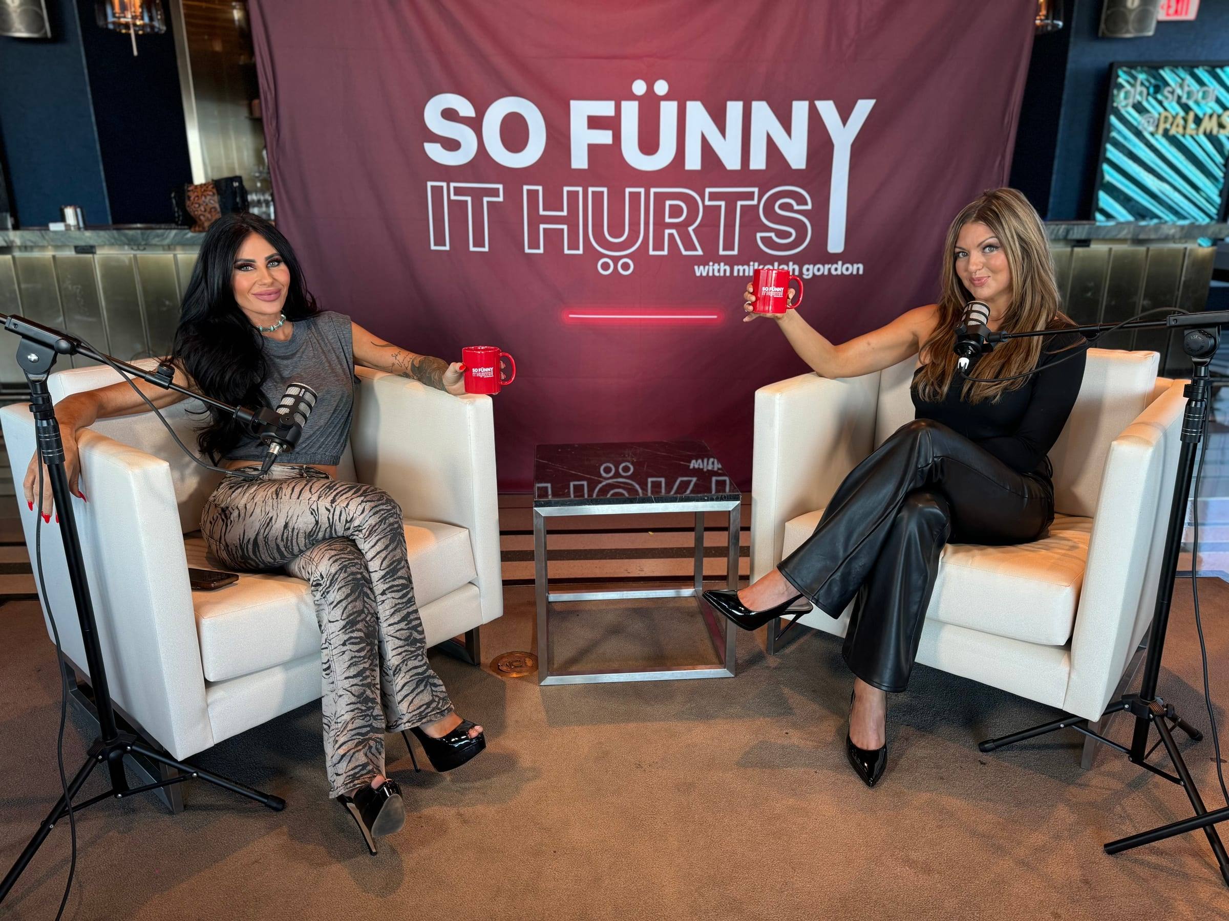 Two hosts recording on white armchairs in front of a branded show backdrop
